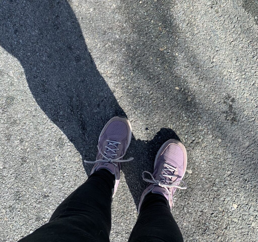 A top down view of the author’s light purple sneakers as she stands on her street.
