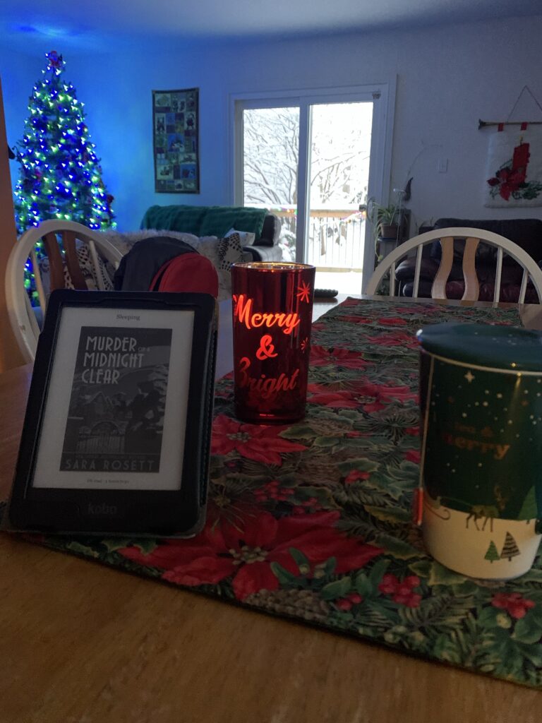 The view of my table and my living room from the vantage point of my usual chair. There’s a mug, a candle, and an ereader tablet on the table.